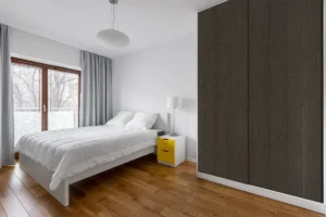 Modern wall cabinet made with New Mika HPL laminate in a sleek wood-grain finish, featuring full-height storage and a contemporary bedroom interior design.