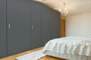 Modern wall cabinet made with New Mika 3560 Fashion Grey SUEDE HPL laminate in a sleek wood-grain finish, featuring full-height storage and a contemporary bedroom interior design.